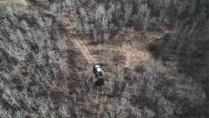 aerial view of a driving on a dirt track through a forrested area.
